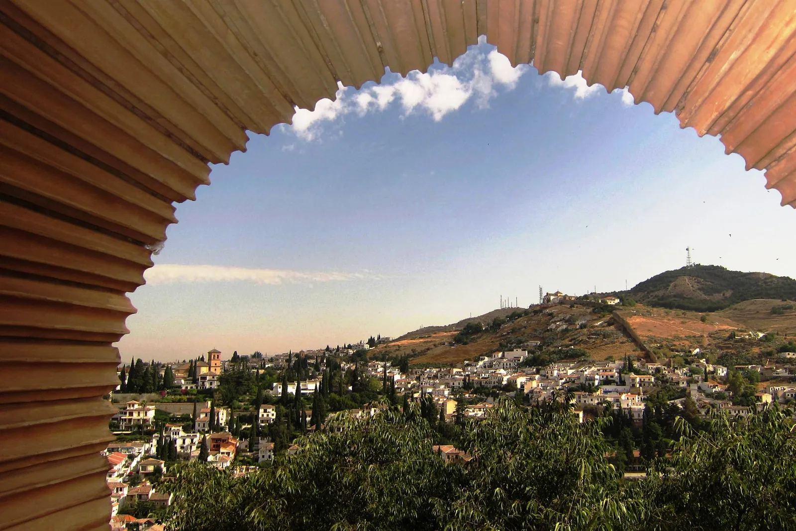 The Sacromonte hill seen through a scalloped arch in the Nasrid Palaces of the Alhambra; a general photograph of the view