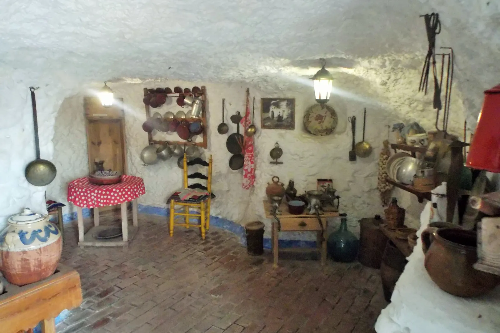 A rebuilt cave kitchen with pots, a lamp and a brick floor at the Sacromonte Caves Museum; a general photograph, not a show cave